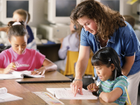  two students and a teacher in a classroom doing deskwork